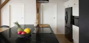 Fruits on black glossy countertop on kitchen island in house interior with white doors